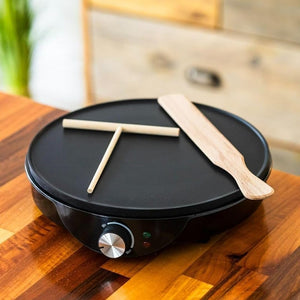 Black electric griddle with wooden spatula on a wooden surface