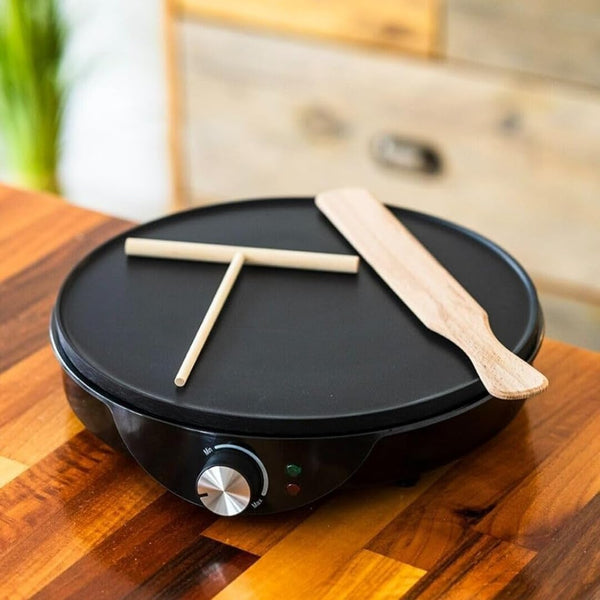 Black electric griddle with wooden spatula on a wooden surface