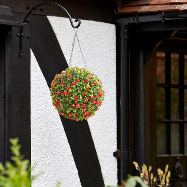 Hanging flower ball with green and red flowers against a black metal structure.