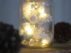 Glass jar with fairy lights and decorative elements on a blurred background