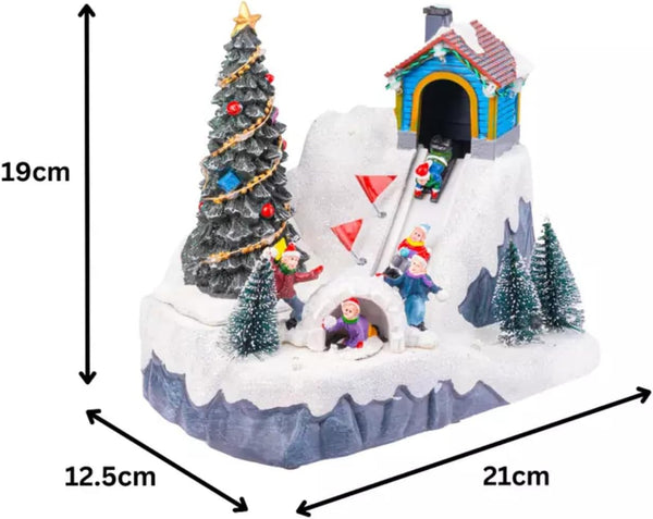 Christmas-themed miniature village with a tree, house, and figures, shown with dimensions on a white background.