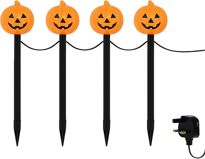 Four pumpkin-shaped lights on stakes in front of a house