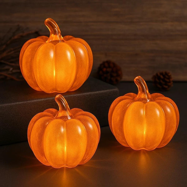 Three glass pumpkins on a dark surface with a wooden background