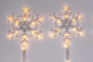 Two snowflake-shaped lighted decorations on a white background