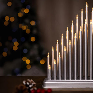 Decorative candle holder with lit candles against a blurred Christmas tree background