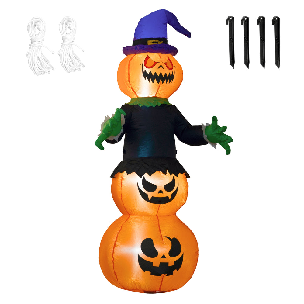 A Halloween inflatable jack-o'-lantern stack with a witch hat and black outfit, photographed outdoors in front of a house at night on a lawn.