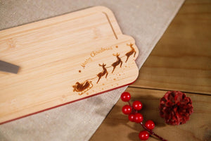 Wooden cutting board with laser-engraved Christmas design on a wooden surface.
