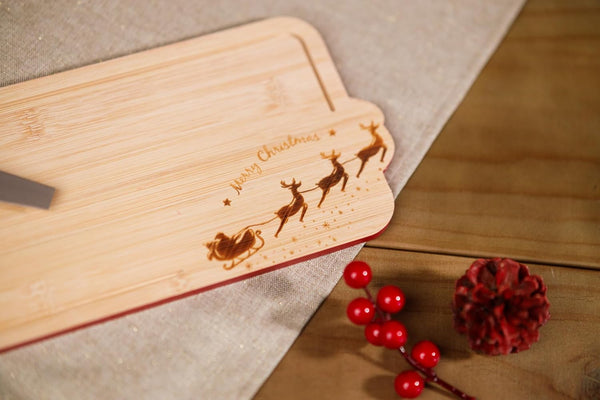 Wooden cutting board with laser-engraved Christmas design on a wooden surface.