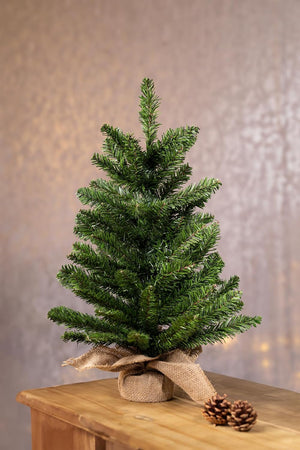 Small artificial Christmas tree on a wooden surface with a soft background