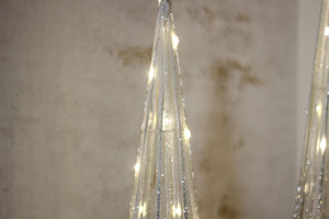 Top of pre lit silver sparkle tree in a room setting against a textured wall.
