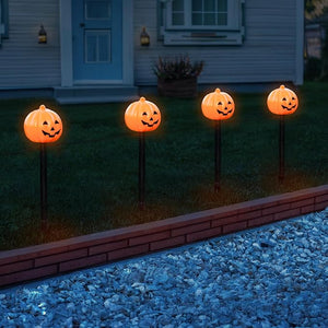 Four pumpkin-shaped lights on stakes in front of a house