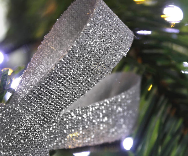 Close-up of a glittery ribbon on a Christmas tree with blurred lights in the background