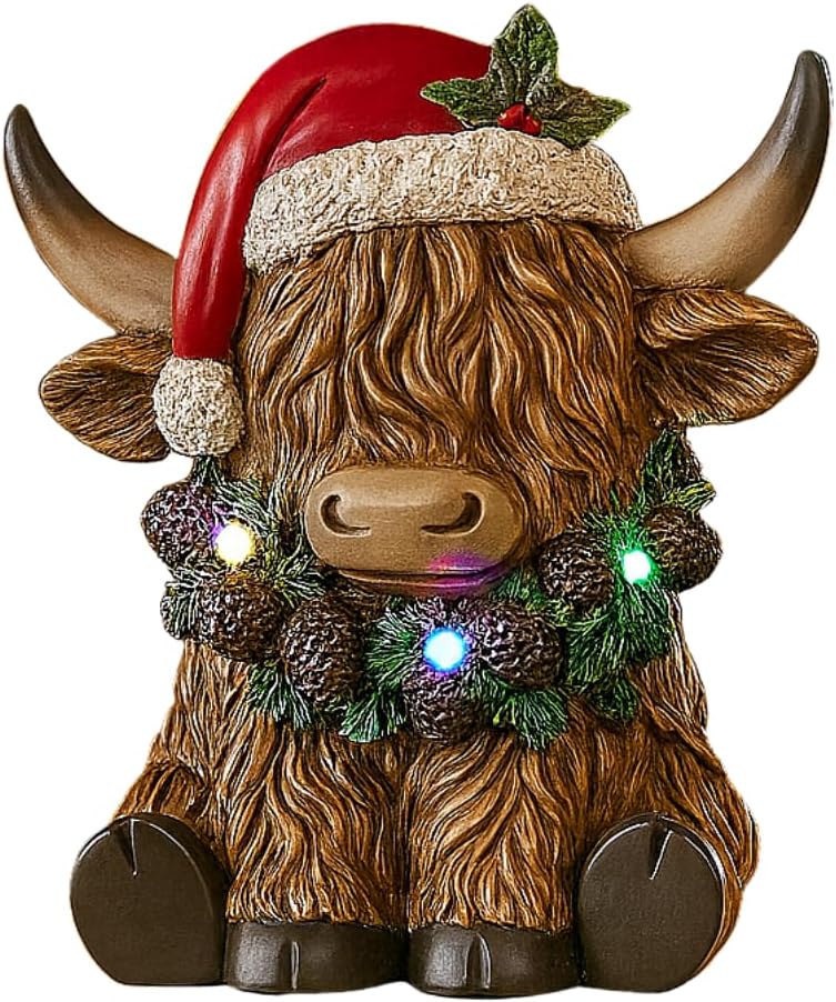 Decorative Highland cow figurine wearing a Santa hat with lights on a mantelpiece.