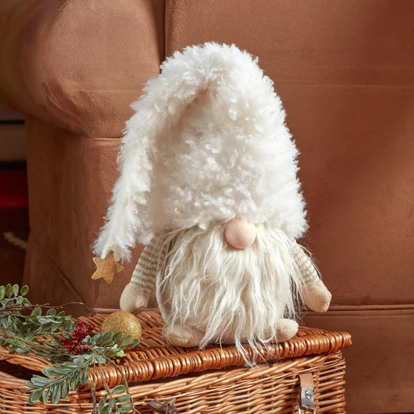 Decorative gnome with white beard and hat on a wicker box with Christmas decorations.