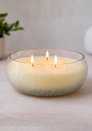 Three-wick candle in a textured glass holder on a neutral background