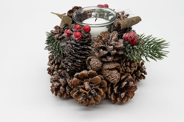 Decorative candle holder with pine cones, berries, and a candle on a white background