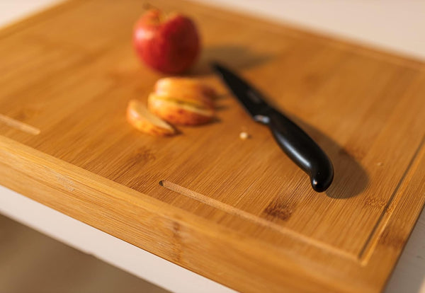 Wooden cutting board with a knife and apples on a blurred background