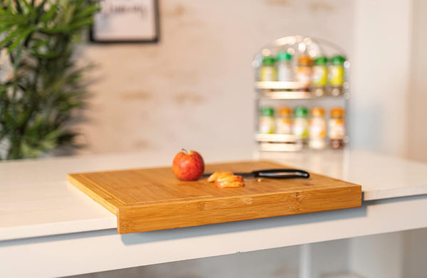 Bamboo cutting board with an apple and knife on a kitchen counter