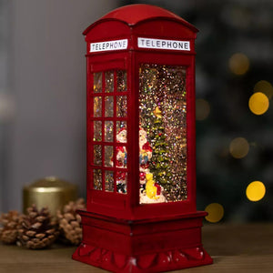 Red telephone booth snow globe with Christmas decorations on a blurred background