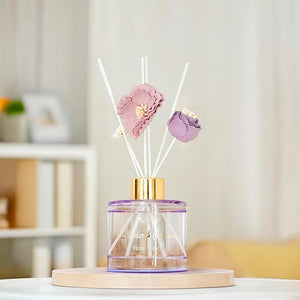 Decorative diffuser with floral elements on a wooden stand against a blurred indoor background