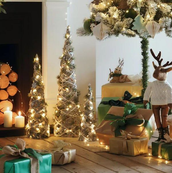 Decorative Christmas scene with small trees, lights, presents, and a reindeer figure.