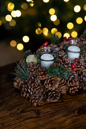 Decorative arrangement of pine cones and candles with a blurred festive background