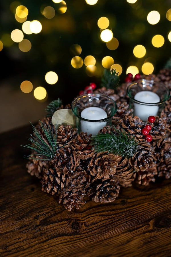 Decorative arrangement of pine cones and candles with a blurred festive background