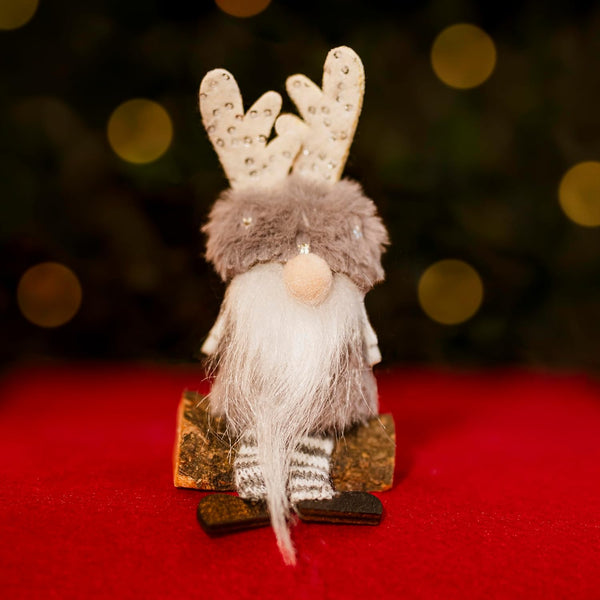 Decorative gnome with reindeer antlers on a red surface with a blurred bokeh background