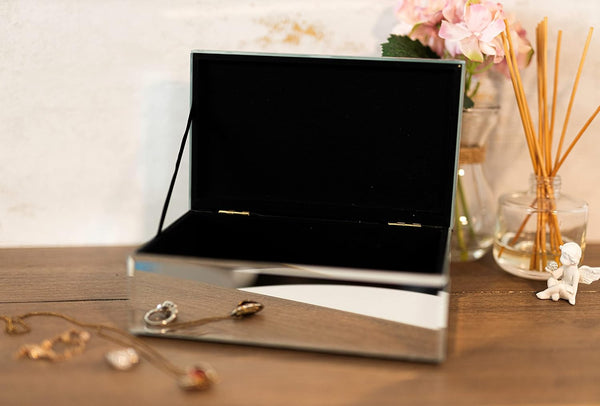 Silver jewelry box on a wooden surface with earrings inside, blurred background