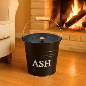 Black metal ash bucket with 'ASH' text in front of a fireplace.