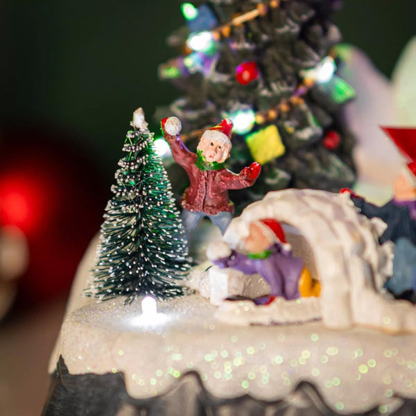 Close up shot of the Christmas-themed diorama with a snow-covered igloo, Christmas tree, and small figures on a white background