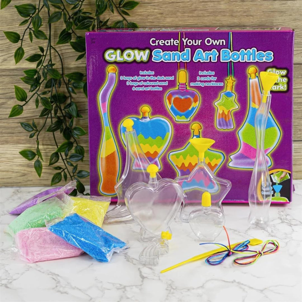 Glow sand art bottles set with packaging on a marble surface.