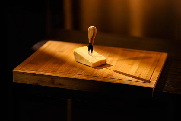 Butter on a wooden cutting board with a knife, dimly lit.