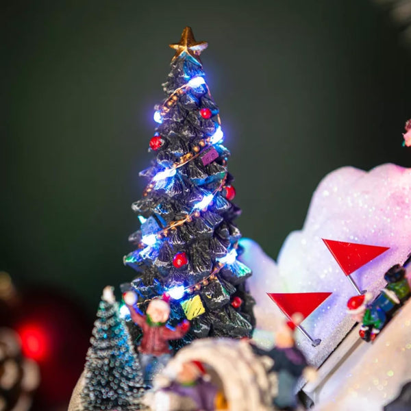 Close up shot of the Christmas-themed diorama with a snow-covered igloo, Christmas tree, and small figures on a white background