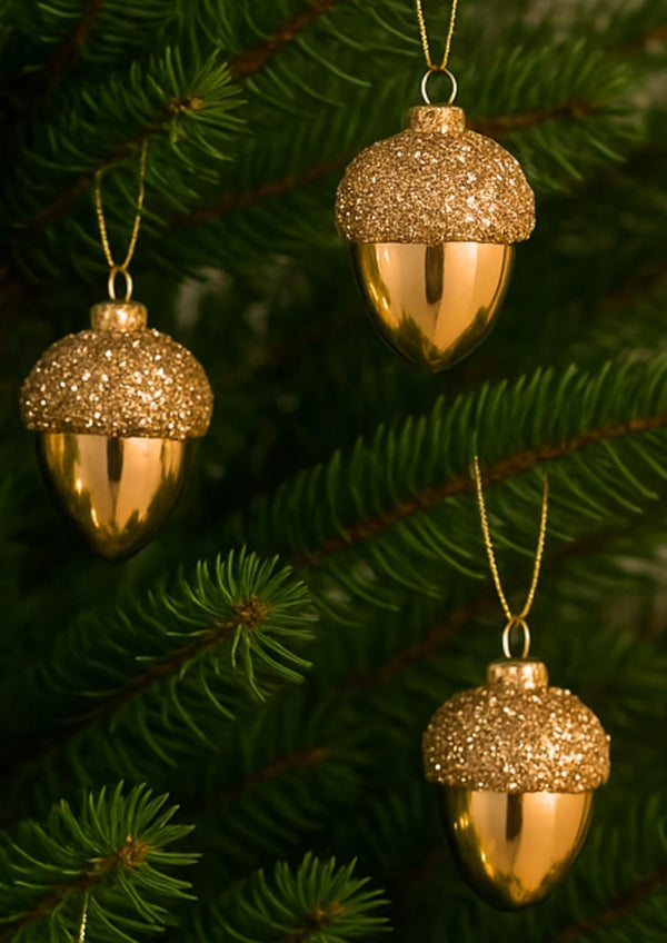 Gold acorn-shaped ornaments hanging on a Christmas tree.