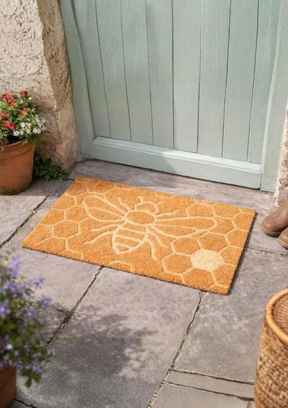 Orange doormat with floral pattern on a stone patio outside a door.