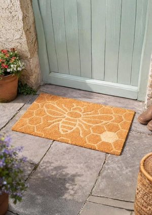Orange doormat with floral pattern on a stone patio outside a door.