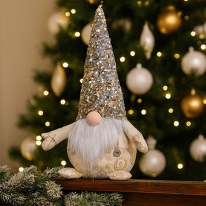 Decorative gnome with a glittery hat in front of a Christmas tree.