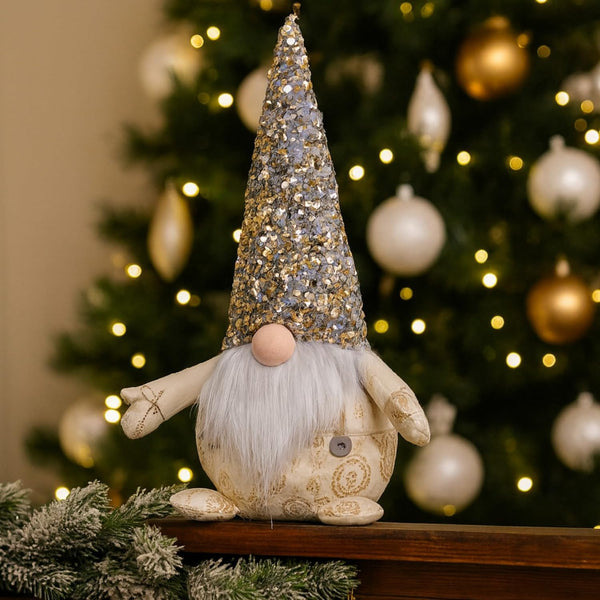 Decorative gnome with a glittery hat in front of a Christmas tree.