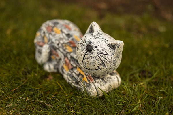 Decorative stone cat figurine on grass