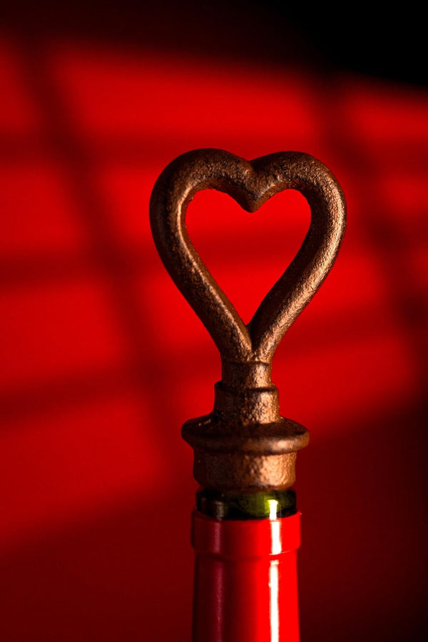 Rustic heart-shaped bottle stopper on a red bottle against a red background