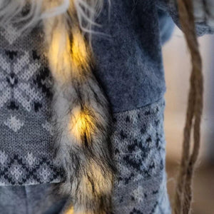 Close-up of a person wearing a dark blue sweater with a patterned scarf and fur trim.