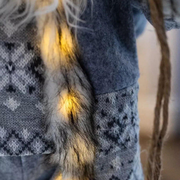 Close-up of a person wearing a dark blue sweater with a patterned scarf and fur trim.