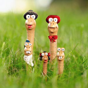 Toy figures resembling worms with googly eyes and colorful hats in a grassy field