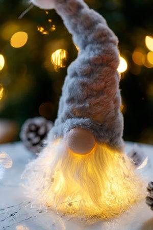 Decorative gnome with glowing lights against a blurred Christmas tree background