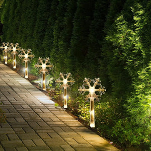 Decorative outdoor lights shaped like snowflakes on a garden path.