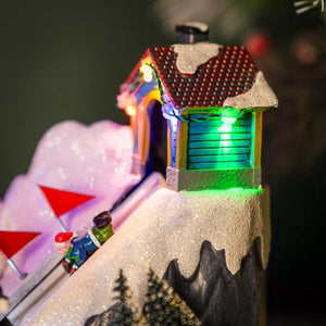 Close up shot of the Christmas-themed diorama with a snow-covered igloo, Christmas tree, and small figures on a white background