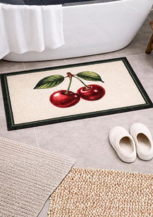 Decorative doormat with cherry design in front of a white bathtub