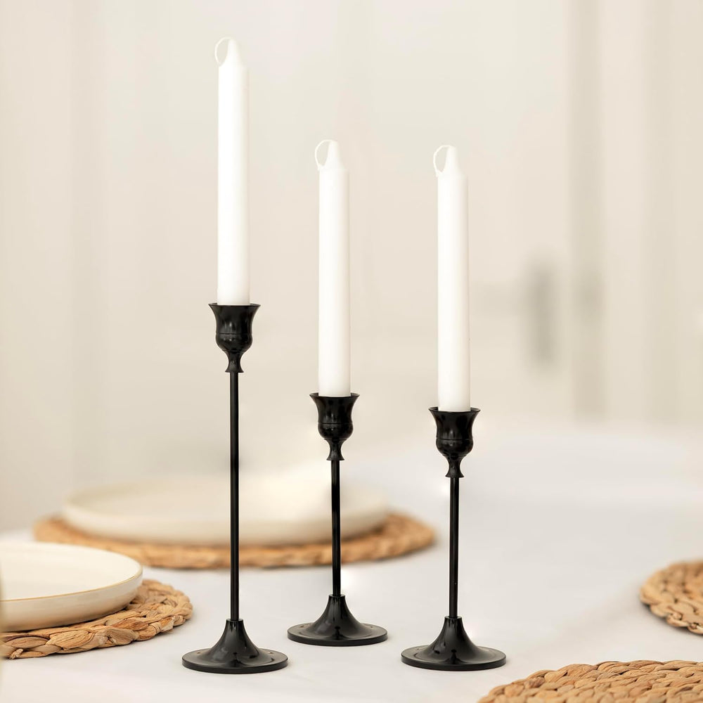 Three black candlesticks with white candles on a neutral background