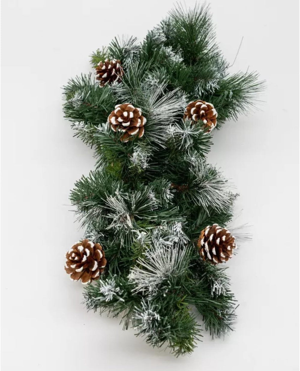 A Christmas artificial hanging swag wreath decoration with green leaves and brown pinecones, displayed against a dark blue background.